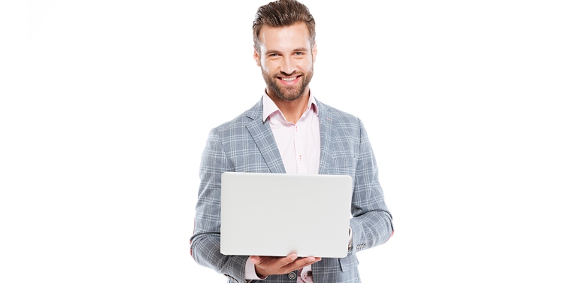 Uomo d'affari sorridente in piedi con il computer portatile mentre guarda la fotocamera