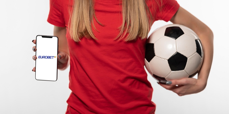 Vista dimezzata frontale di una ragazza che tiene un pallone di calcio e mostra il suo iPhone