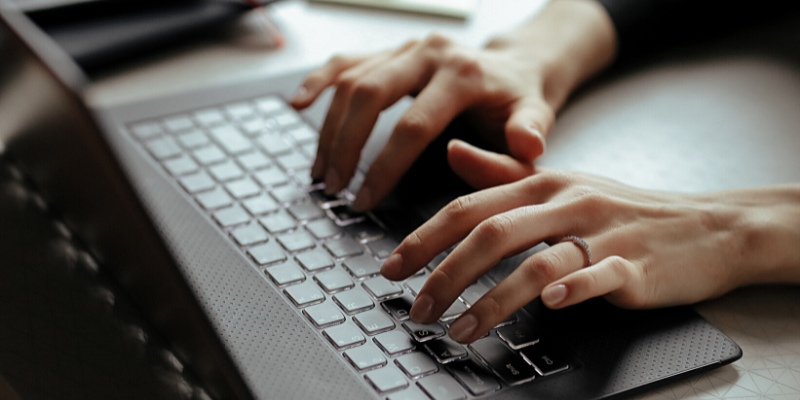 Vista parziale di una giovane donna che scrive con la tastiera del Notebook